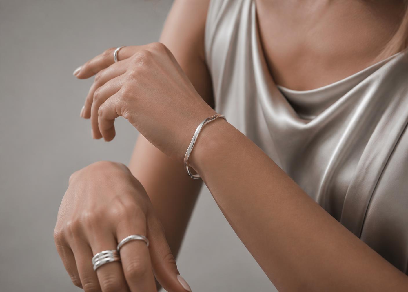 Silver bangle and stacked rings on a model's hands